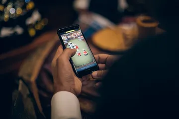 A man celebrating a winning moment on his laptop while gaming symbols float around him, capturing the excitement of D63 games.